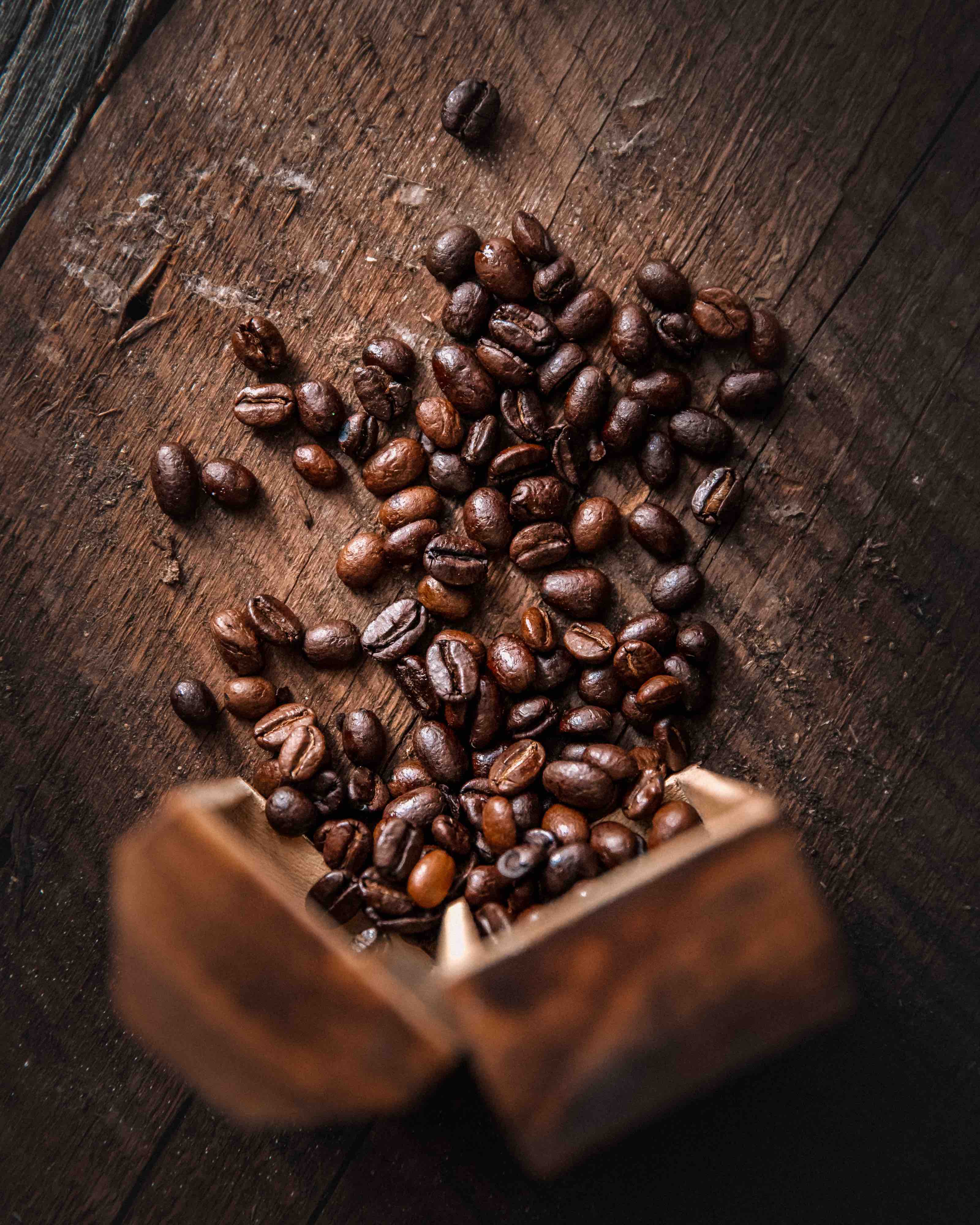 Overhead image of coffee spilling onto a wooden tabletop.