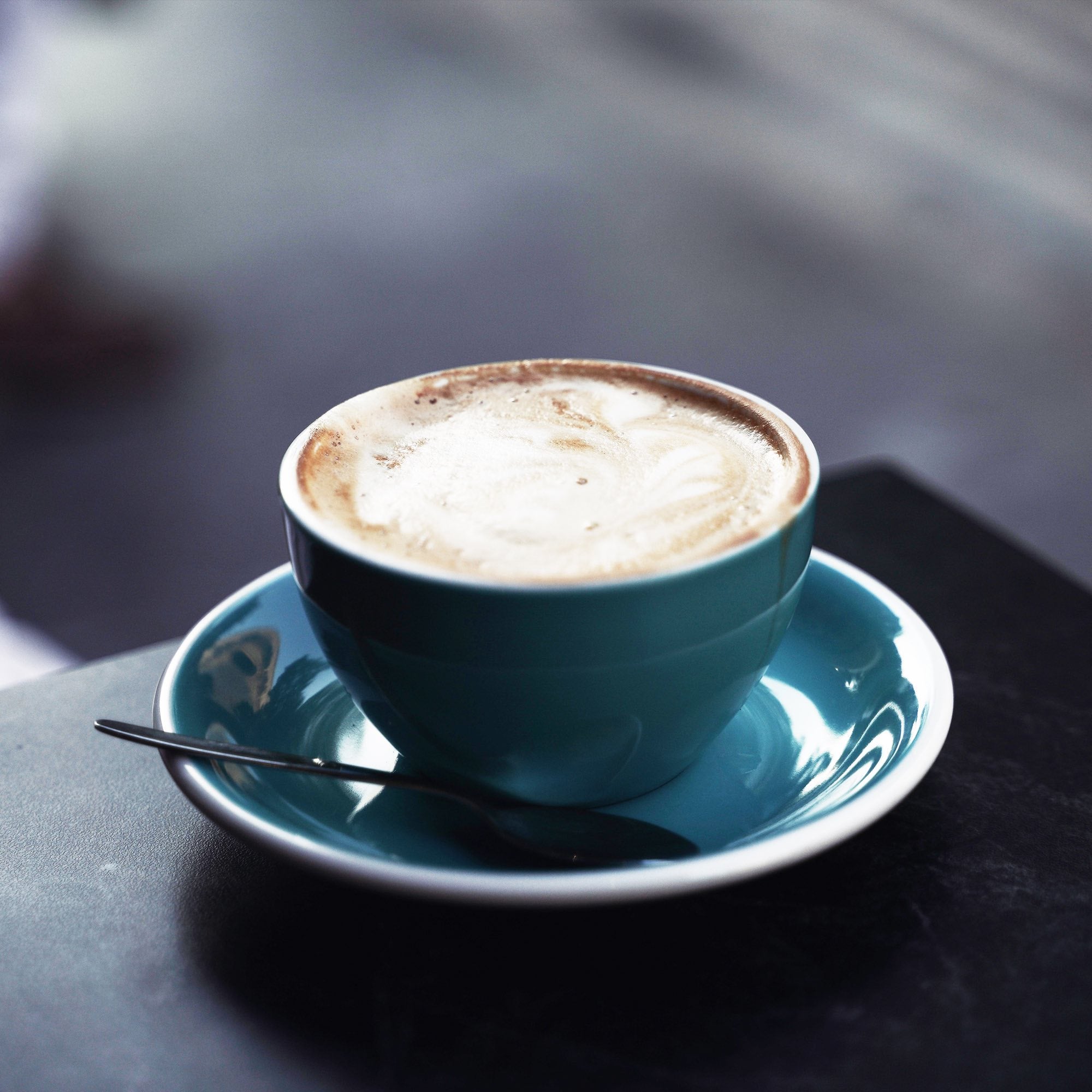 A coffee mug on the edge of a black countertop.